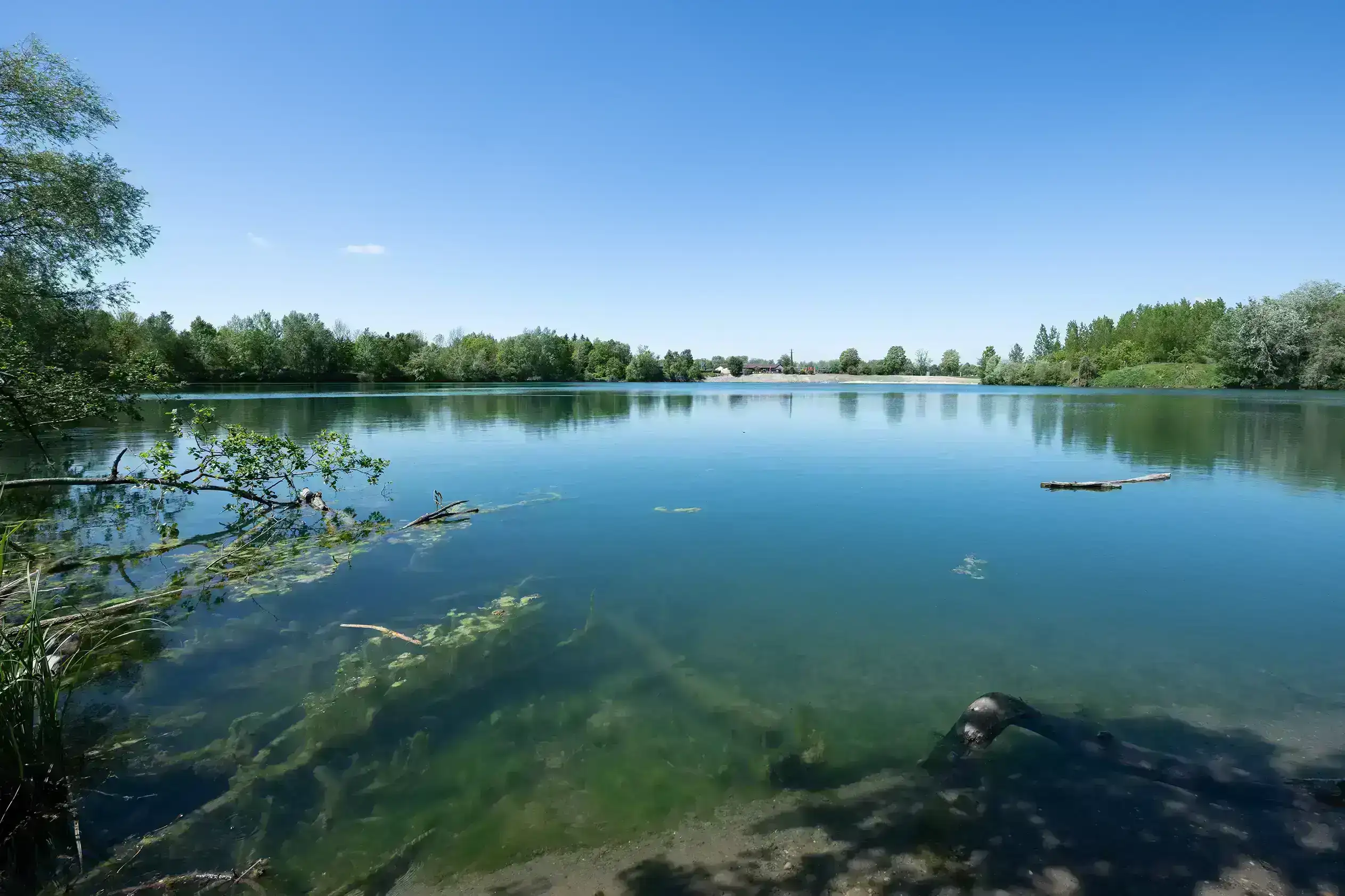 Ein strahlender blauer Himmel spiegelt sich im Gewässer, das Teil der Fischwanderhilfe bei Abwinden-Asten ist.