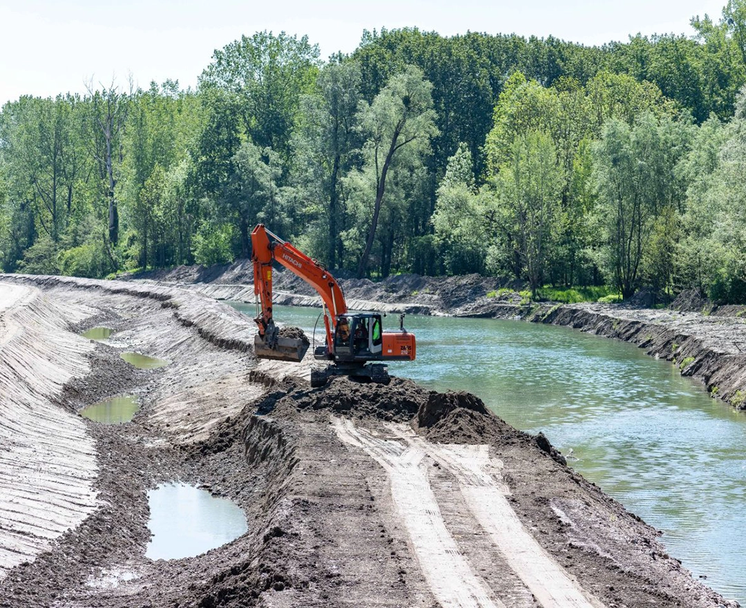 Preparation for the fish bypass at Abwinden-Asten: An excavator is already working on the bank of a narrow river.