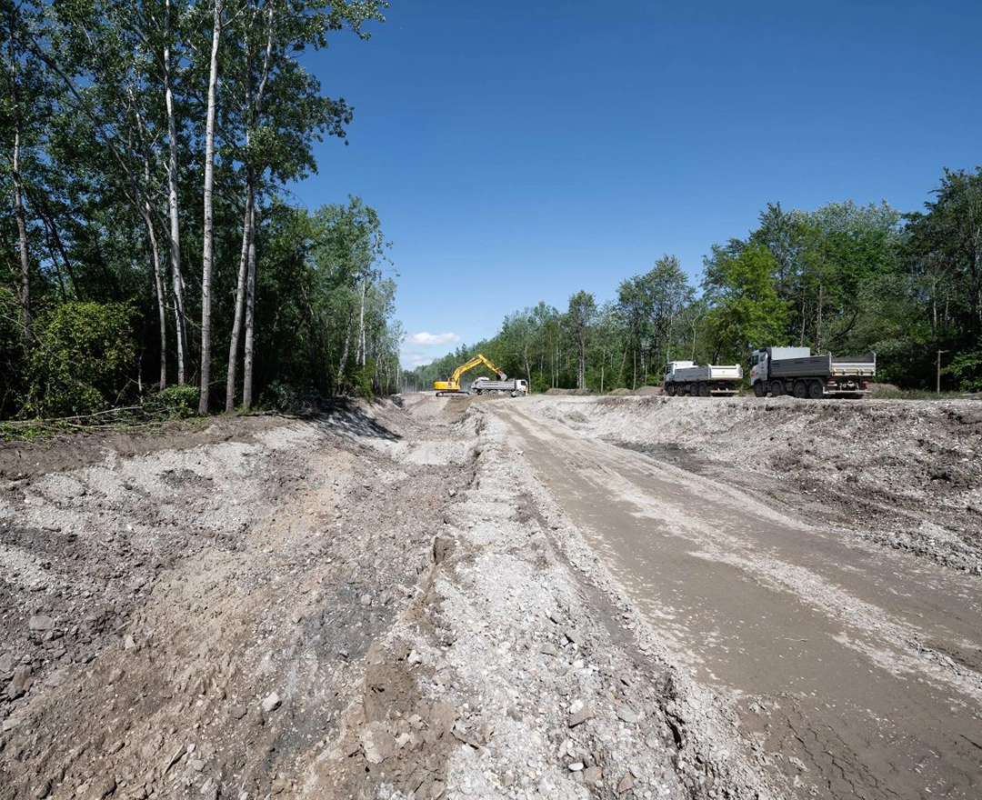 The first preparatory work for the Abwinden-Asten fish pass is being carried out: an excavator is fighting its way through the subsoil under a bright blue sky.