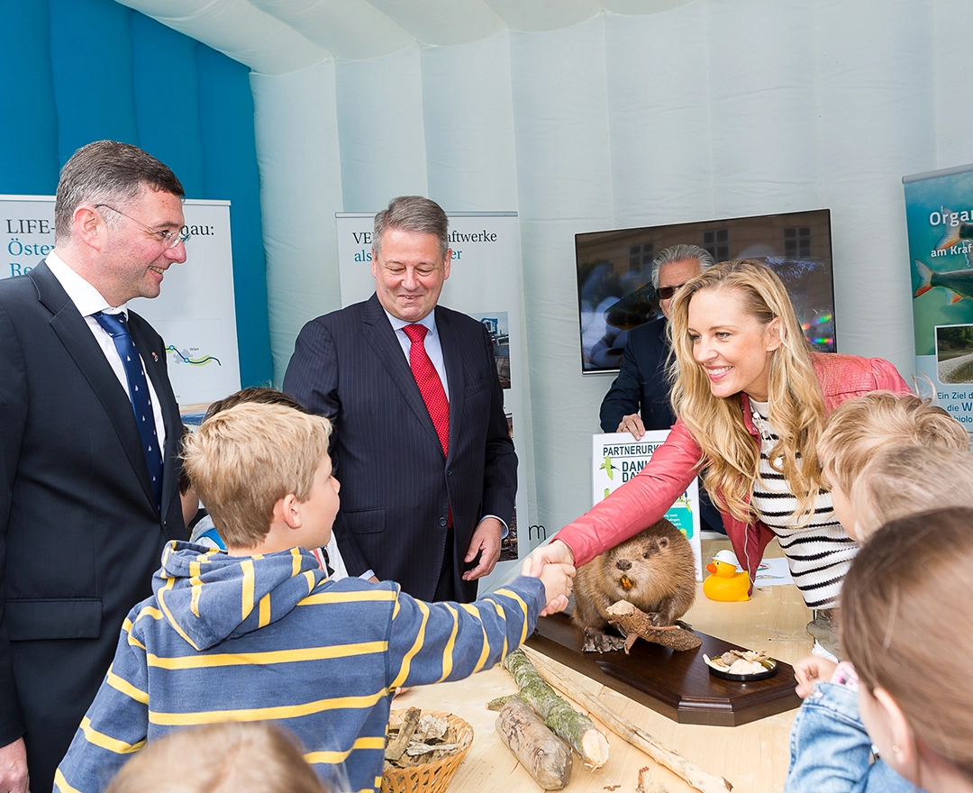 Beim Danubeday 2019 konnte man sich über den Lebensraum Donau informieren. Das Bild zeigt interessierte Erwachsene und Kinder. Eine blonde Frau gibt einem Jungen dabei die Hand.